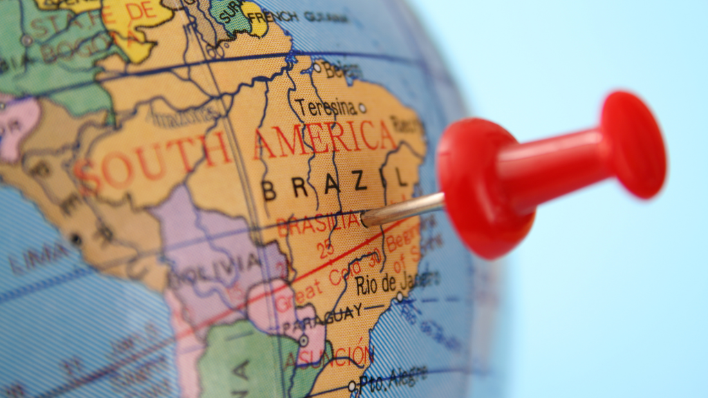 Close-up of a globe map showing South America and Brazil, marked by a red pushpin.