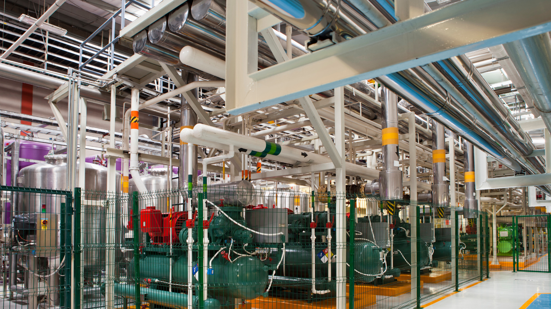 Industrial facility with stainless steel pipes, tanks, and machinery.