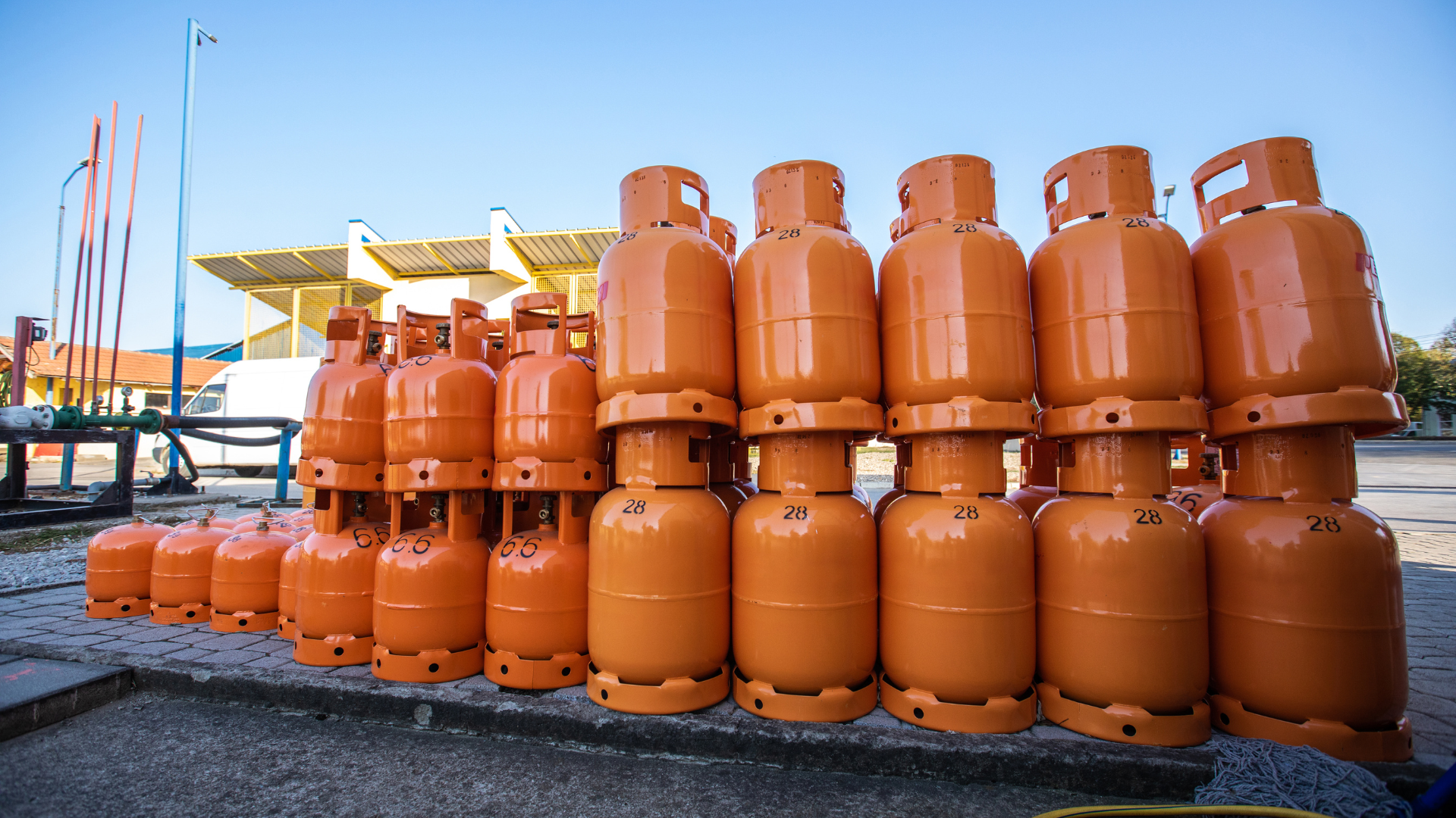 Stacked orange LPG gas cylinders stored at an outdoor distribution facility