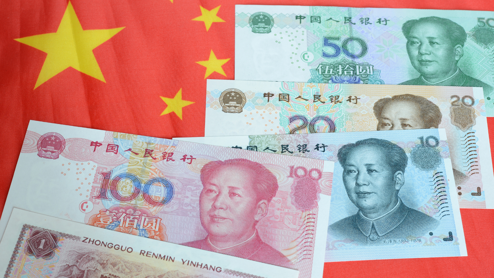 Chinese yuan banknotes displayed in front of the Chinese national flag, representing China’s currency and financial system.