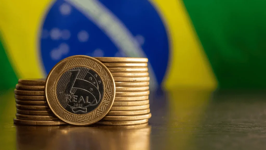 Brazilian real coins stacked with the Brazil flag in the background, representing Brazil’s financial markets and currency
