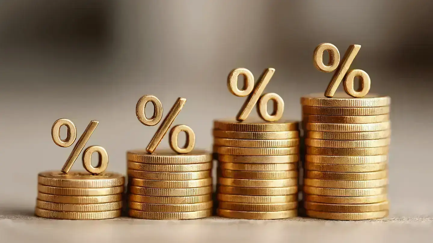 Stacks of gold coins with percentage symbols increasing in height