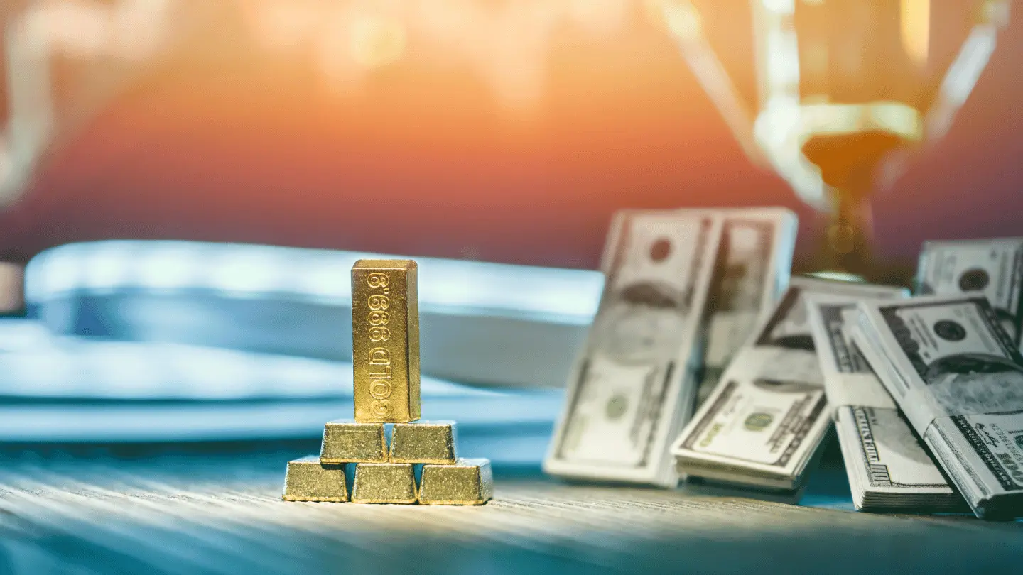 Gold bars stacked on a table with US dollar banknotes