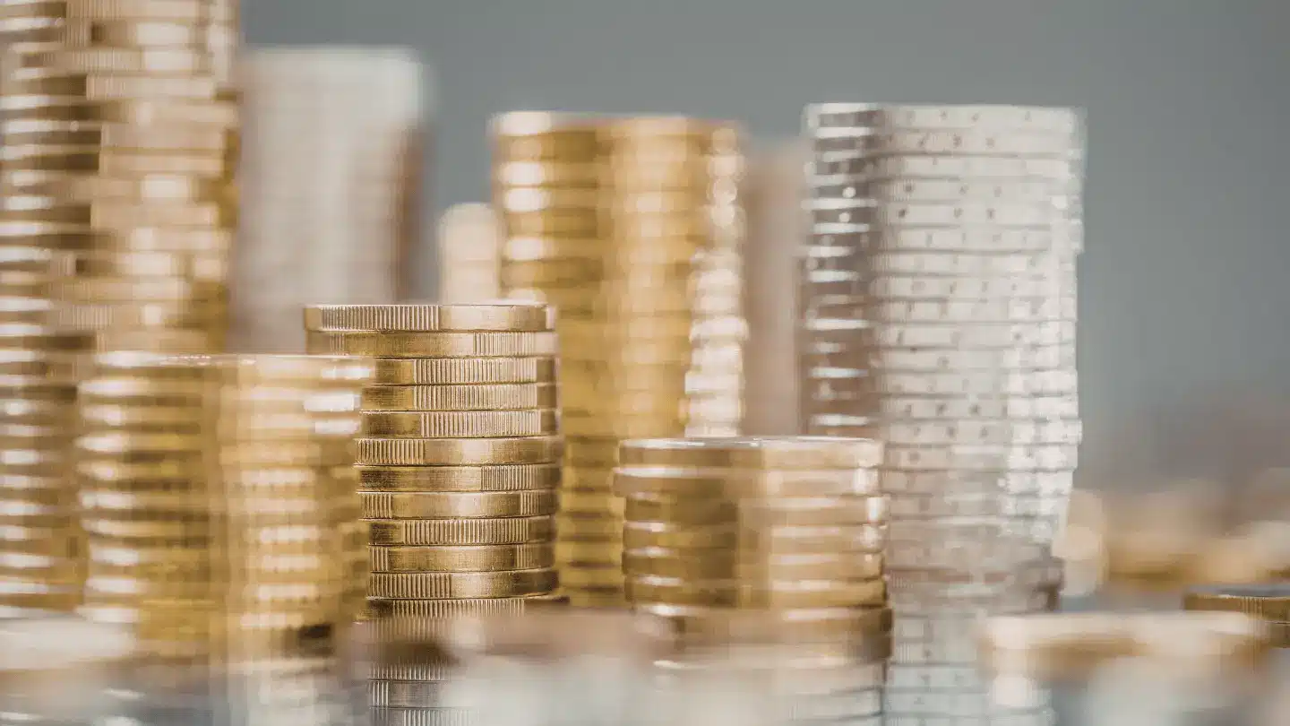 Stacks of gold and silver coins arranged in columns, representing financial markets, wealth, and investment growth.